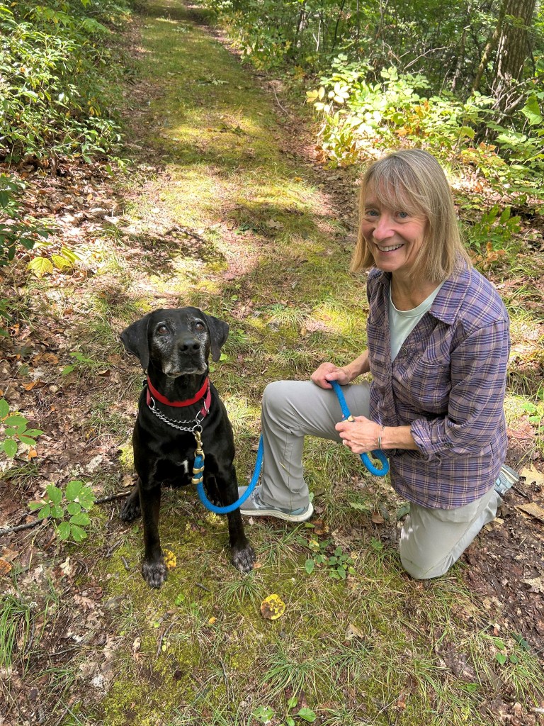 A woman posing with her dog for a photo in a park.